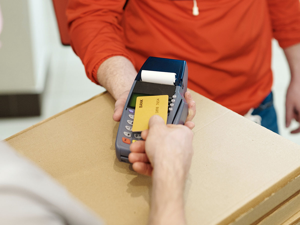 Image from: https://www.pexels.com/photo/person-paying-for-food-delivery-with-a-credit-card-4393443/ Person using a credit card with a handheld card reader